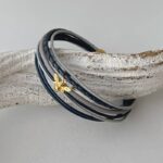 das Lederarmband mit einer goldener Biene in blau-grau