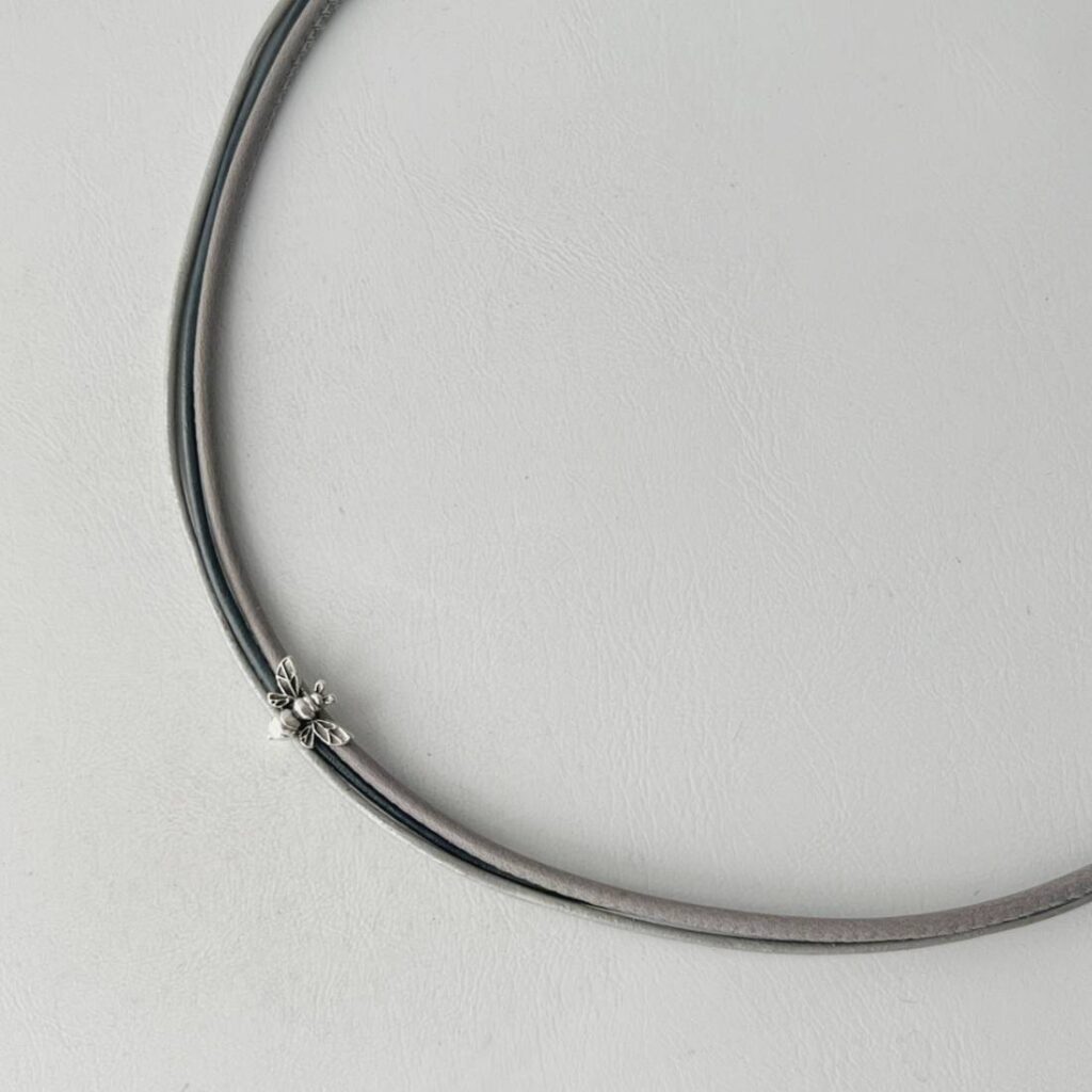das Ledercollier mit einer Biene in grau