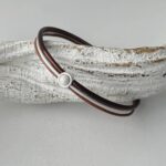 das Lederarmband in braun mit einem weißem Stein